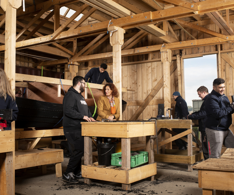 Foto van Divosa-lid Marjolein Dölle met medewerkers van de werkplaats Scheepswerf Clean2Anywhere