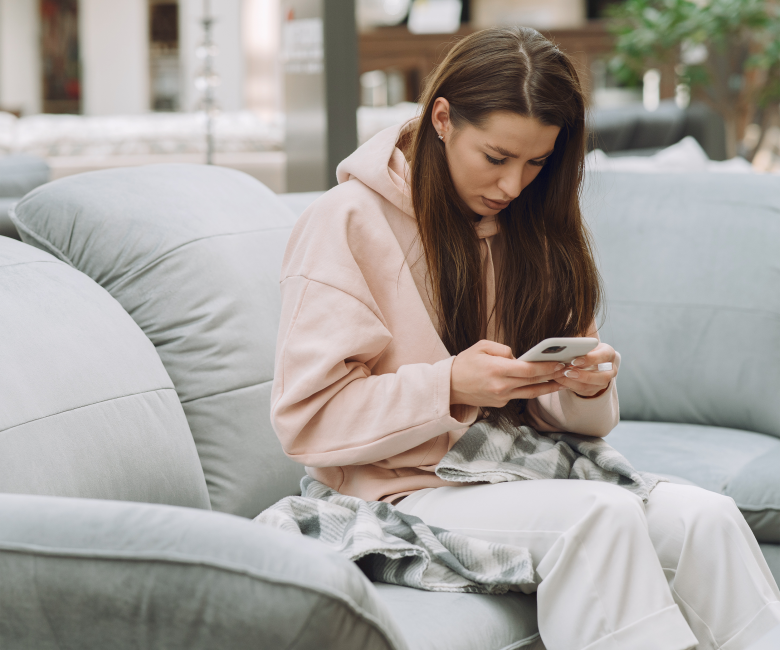 Zieke vrouw zit met een smartphone in haar hand op een bank