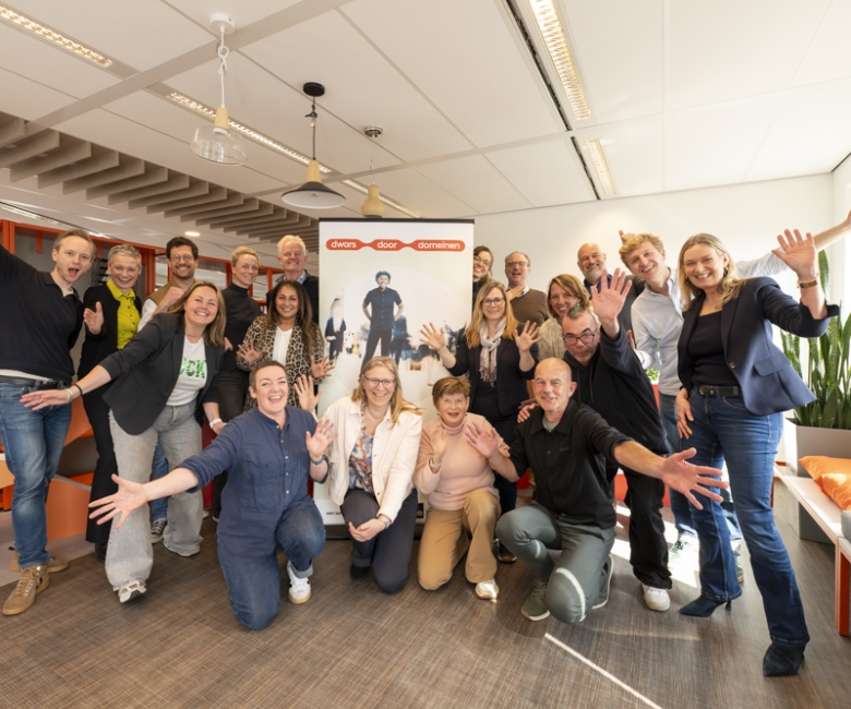 Deelnemers aan de kick-off zwaaien enthousiast voor de banner van Dwars door domeinen