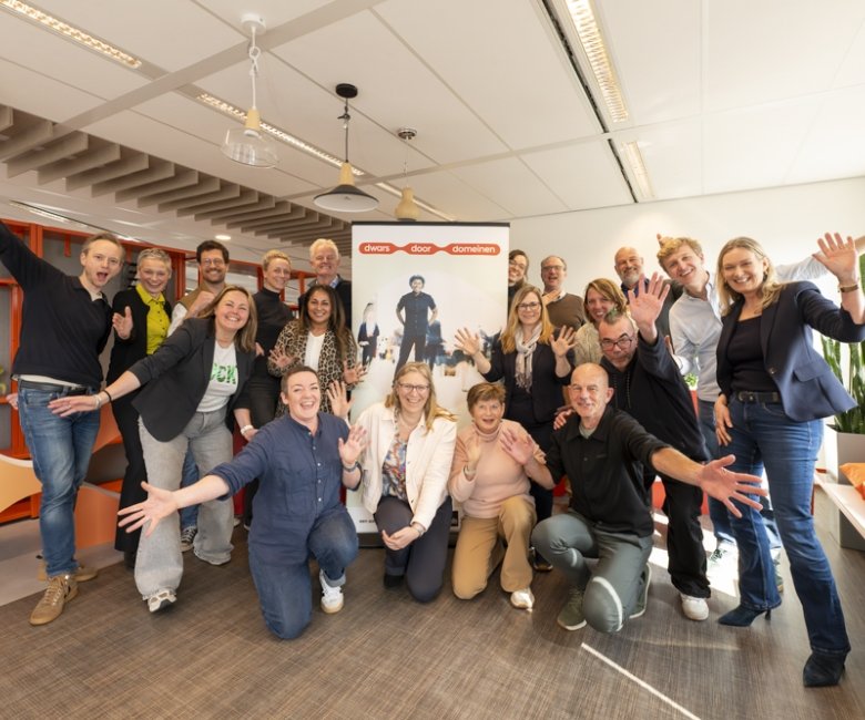 Deelnemers aan de kick-off zwaaien enthousiast voor de banner van Dwars door domeinen