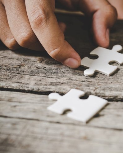 twee handen en witte puzzelstukjes op tafel