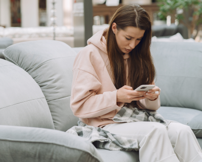 Zieke vrouw zit met een smartphone in haar hand op een bank