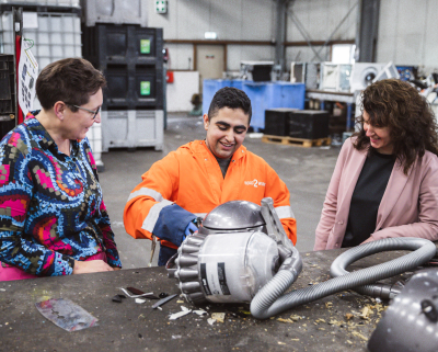 Mohamad haalt apparaten uit elkaar voor recycling, Miriam en Woutine kijken toe