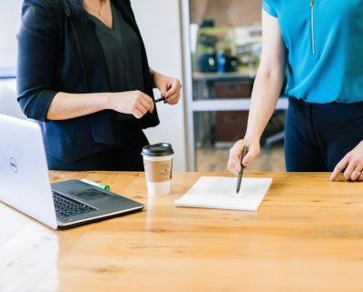Two people standing at table with laptop