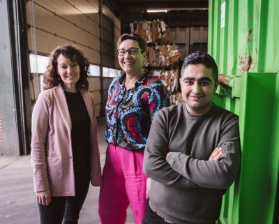 Een jonge inburgeraar Mohamed op zijn werkplek, met zijn begeleiders achter hem