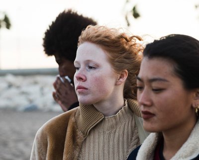 Foto van drie serieus kijkende jongeren op het strand