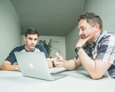 Jongere en volwassene achter een laptop