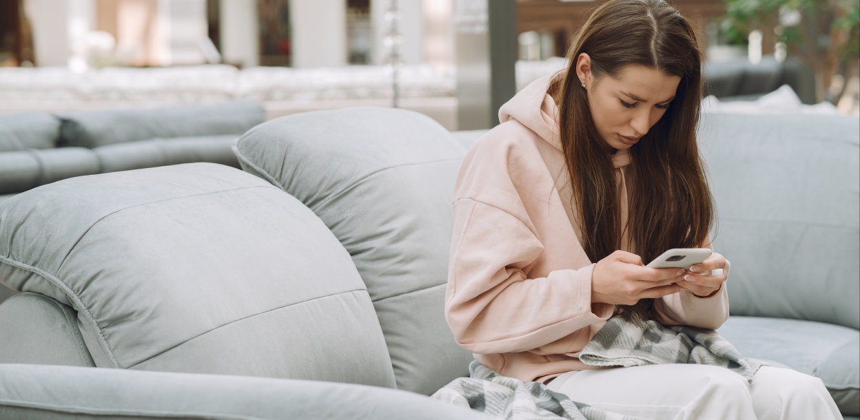 Zieke vrouw zit met een smartphone in haar hand op een bank