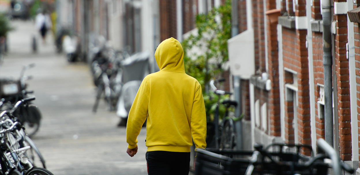 Jongere met gele hoodie loopt op straat