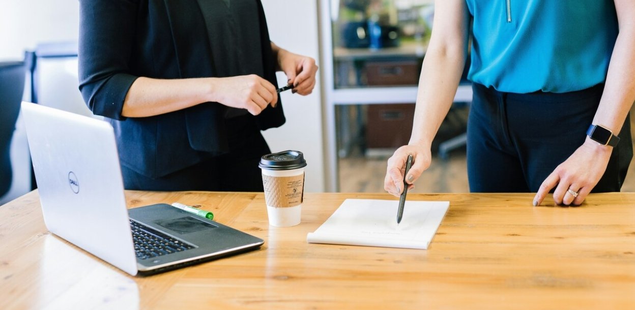 Two people standing at table with laptop