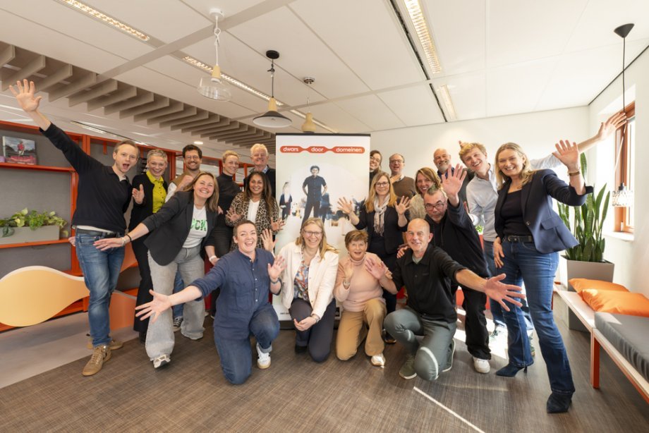 Deelnemers aan de kick-off zwaaien enthousiast voor de banner van Dwars door domeinen