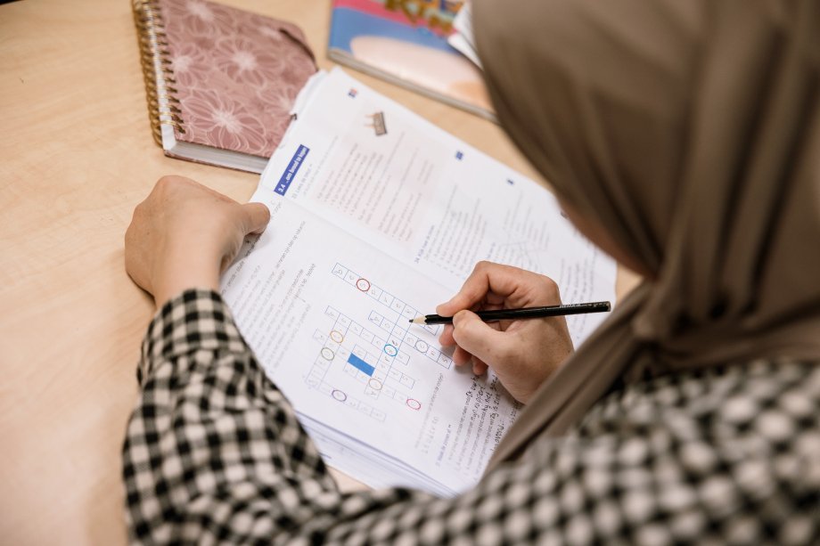 Iemand werkt aan een opdracht tijdens de Nederlandse les